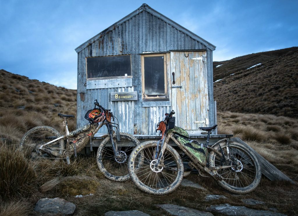 Custom roll top Southern Lite Packs frame bags on bikepacking bikes outside a backcountry hut